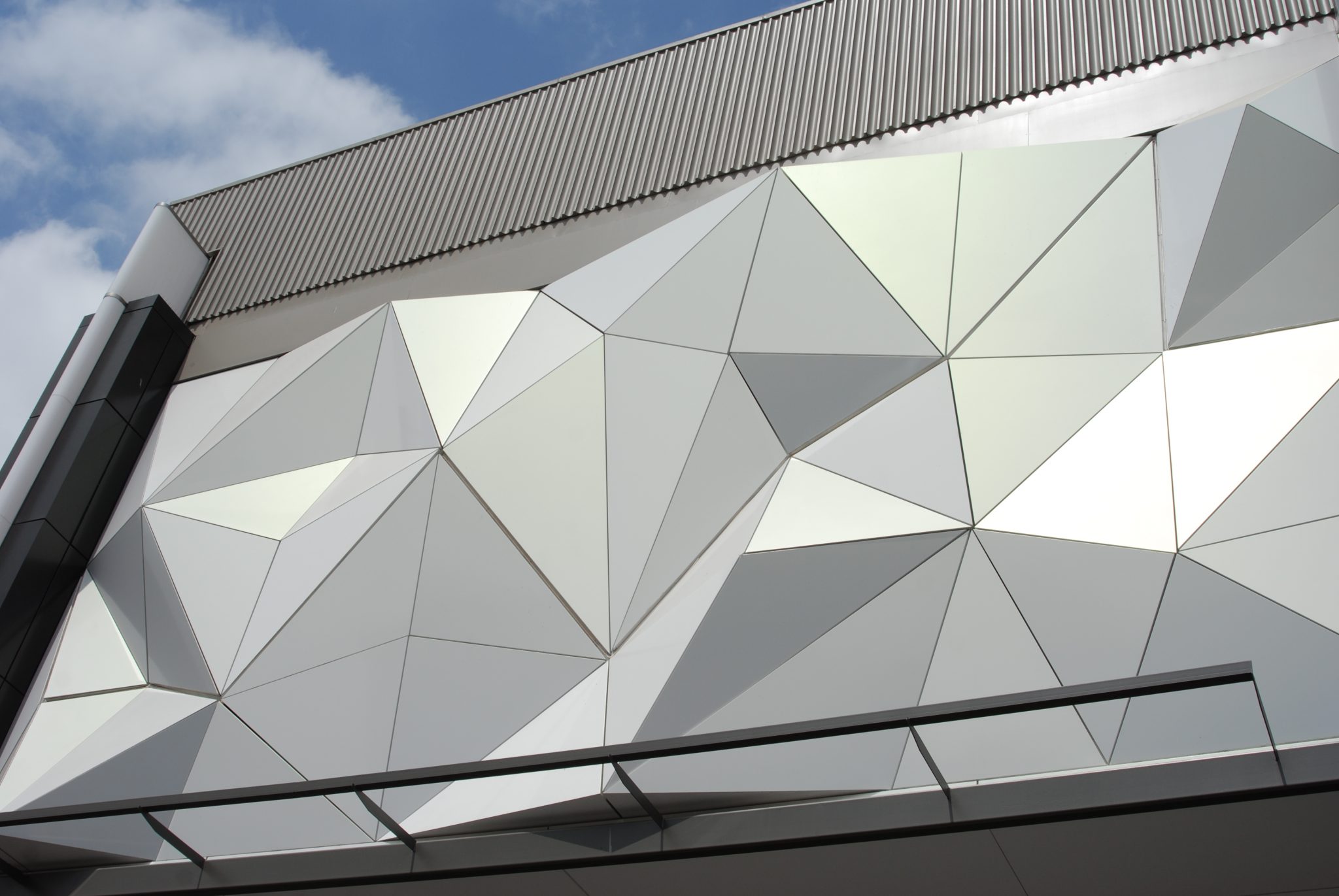 A faceted aluminum commercial facade against a bright sky